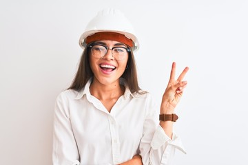 Young beautiful architect woman wearing helmet and glasses over isolated white background smiling with happy face winking at the camera doing victory sign. Number two.