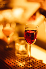 An alcoholic drink on the rocks in a cocktail glass on the bar counter. Warm lifestyle dark image, selective focus, natural light
