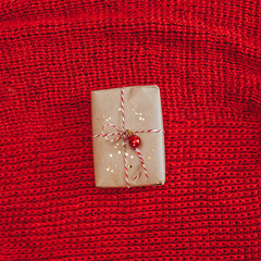 Modern red knitted background with christmas gift and decorations.