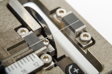 The stripped optical fiber lies in the optical fiber cleaver, close-up