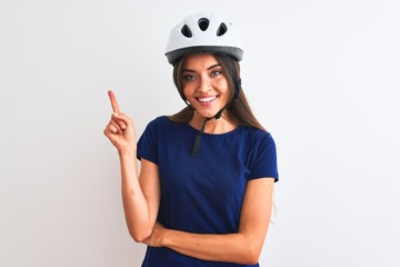 Young beautiful cyclist woman wearing security bike helmet over isolated white background with a big smile on face, pointing with hand and finger to the side looking at the camera.