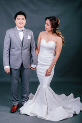 Young asian groom and bride posing and smiling in studio for pre-wedding shot