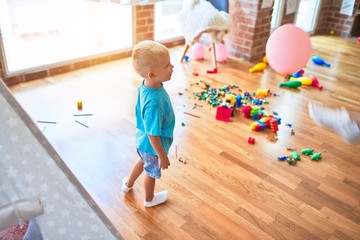 Young caucasian kid playing at kindergarten with toys. Preschooler boy happy at playroom.