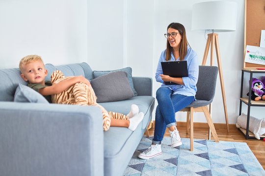Young therapist woman speaking with child, counselor and behaviour correction at the office around toys