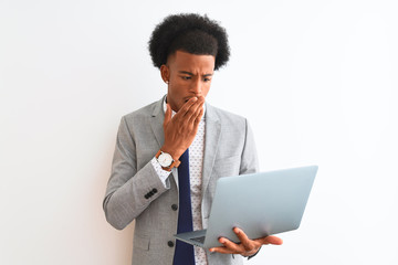 Young african american businessman using laptop standing over isolated white background cover mouth with hand shocked with shame for mistake, expression of fear, scared in silence, secret concept