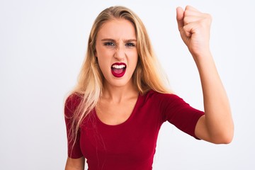 Young beautiful woman wearing red t-shirt standing over isolated white background angry and mad raising fist frustrated and furious while shouting with anger. Rage and aggressive concept.