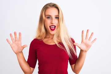 Young beautiful woman wearing red t-shirt standing over isolated white background showing and pointing up with fingers number ten while smiling confident and happy.
