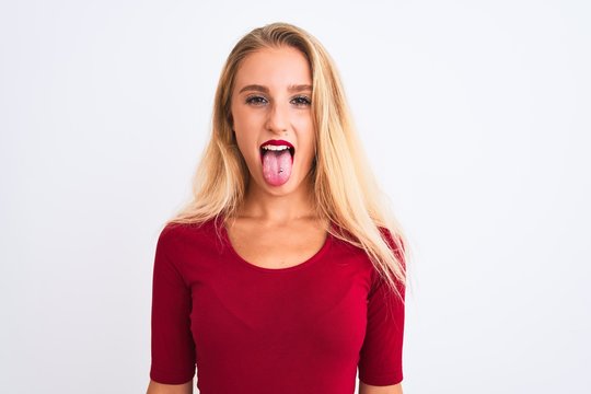 Young beautiful woman wearing red t-shirt standing over isolated white background sticking tongue out happy with funny expression. Emotion concept.