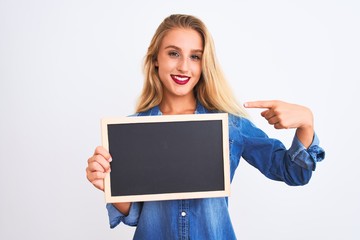 Young beautiful teacher woman holding blackboard standing over isolated white background with surprise face pointing finger to himself