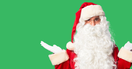 Middle age handsome man wearing Santa Claus costume and beard standing smiling showing both hands open palms, presenting and advertising comparison and balance