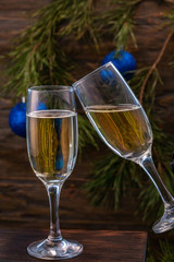 Glasses of champagne with bubbles on the background of Christmas decorations. Glasses touch during a festive toast. Beautiful card.