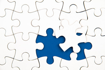 White puzzle over blue backround with missing pieces. Incomplete elements, solution search concept