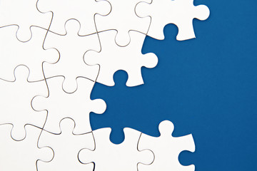 White puzzle over blue backround with missing pieces. Incomplete elements, solution search concept