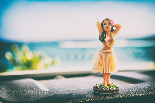 Hawaii hula dancer girl doll on dashboard of car road trip - summer vacation travel dancing woman at ocean beach. Tourism and travel freedom concept.