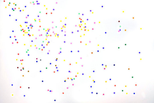 Multi-colored stars on a white background. Festive background of colorful confetti stars on a white background.