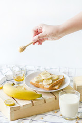Woman's hands as she is having healthy breakfast. Toast banana with honey caramel, and soy milk.