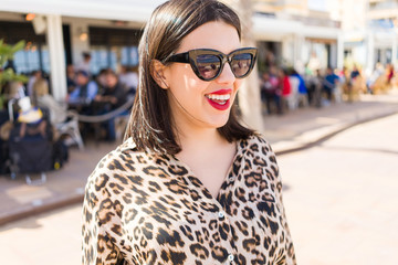 Young beautiful woman with red lips wearing sunglasses smiling happy at the street