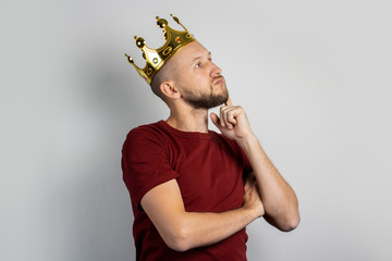 Young man with a crown on his head on a light background. Concept is king, luck, gain, rich, dream,...