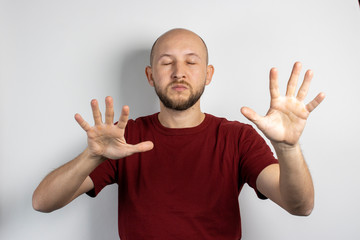 Young man with closed eyes and outstretched arms on a light background. Concept of looking for something with eyes closed, poor eyesight, blindness, closing eyes for something