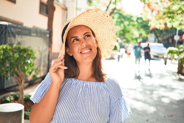 Young beautiful woman smiling happy walking on city streets on a sunny day of summer