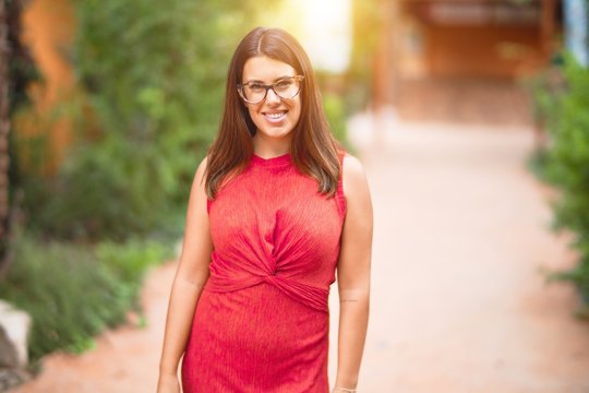 Young beautiful girl smiling happy and confident walking at the town park, standing with a smile on face