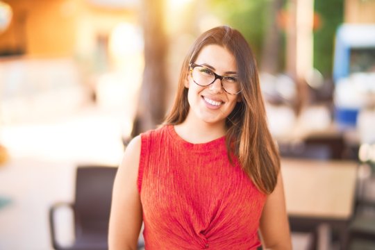 Young beautiful girl smiling happy and confident walking at the town park, standing with a smile on face
