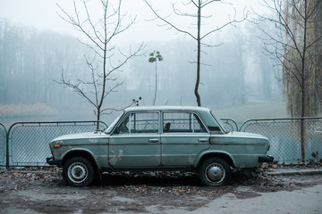 The car is lost near the lake in the foggy dark park in the morning