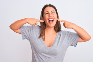 Portrait of beautiful young woman standing over isolated white background smiling cheerful showing and pointing with fingers teeth and mouth. Dental health concept.