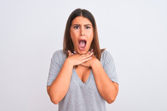 Portrait of beautiful young woman standing over isolated white background shouting and suffocate because painful strangle. Health problem. Asphyxiate and suicide concept.