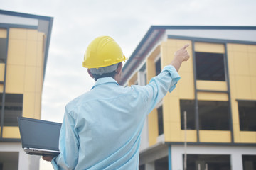 Engineering holding computer notebook with yellow hard hat working building construction estate