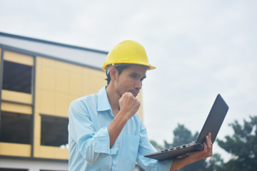 Engineering holding computer notebook with yellow hard hat working building construction estate