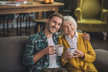 Grey-haired elderly woman having tea with son