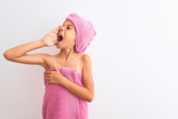 Beautiful child girl wearing shower towel after bath standing over isolated white background shouting and screaming loud to side with hand on mouth. Communication concept.