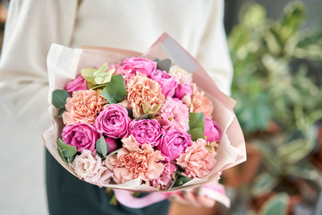 European floral shop. Beautiful bouquet of mixed flowers in womans hands. the work of the florist at a flower shop. Delivery fresh cut flower.