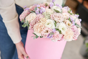 European floral shop. Floral bunch in round box. Bouquet of beautiful Mixed flowers in woman hand. Excellent garden flowers in the arrangement , the work of a professional florist.