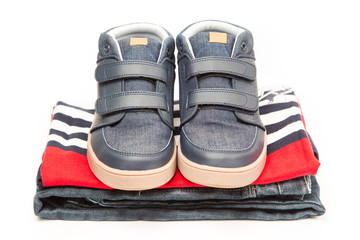 Stack of clothes, fresh laundry textile with shoes on top. Isolated on white background..