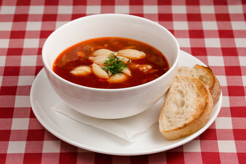 Classic delicious Italian minestrone soup with bread on traditional italian tablecloth background