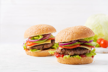 Big sandwich - hamburger burger with beef, avocado, tomato and red onions on light background. American cuisine. Fast Food
