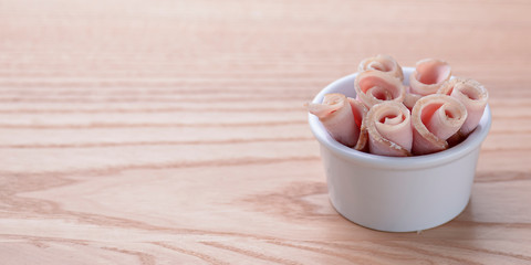 White small little bowl with raw bacon on grey wooden table background
