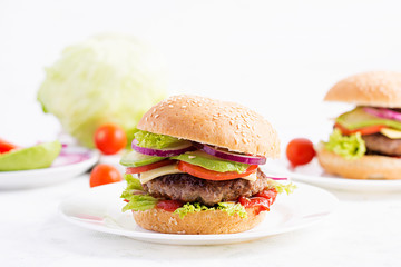 Big sandwich - hamburger burger with beef, avocado, tomato and red onions on light background. American cuisine. Fast Food