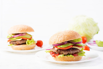 Big sandwich - hamburger burger with beef, avocado, tomato and red onions on light background. American cuisine. Fast Food
