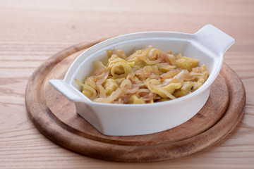 Italian homemade pasta with meat and vegetables served on white plate on grey wooden background.
