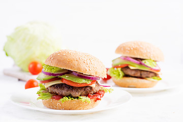 Big sandwich - hamburger burger with beef, avocado, tomato and red onions on light background....