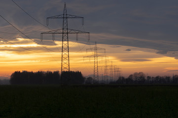 Fototapeta na wymiar electricity pylons power line at orange sunset