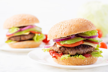 Big sandwich - hamburger burger with beef, avocado, tomato and red onions on light background. American cuisine. Fast Food