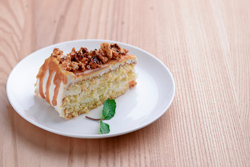Vegan salted caramel cake decorated with popcorn and mint on light wooden background.