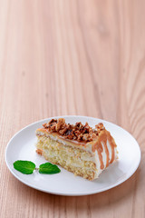 Vegan salted caramel cake decorated with popcorn and mint on light wooden background.