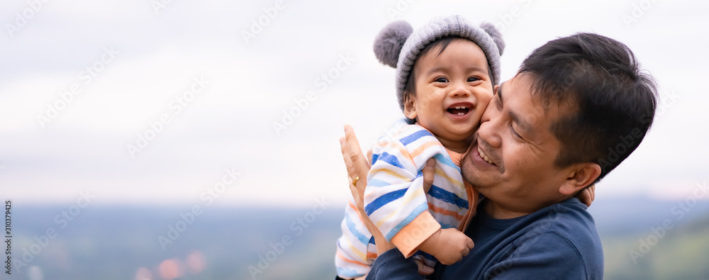 Wall mural asian father is playing with little baby boy with happiness moment on the background of nature , con