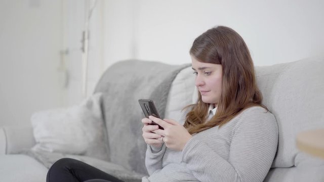 Sad woman using cellphone and sending message, or posting to social media, or breaking up with boyfriend.