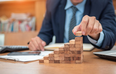 Concept of Business growth, Businessman success for career, Close up hand of man has piling up and stacking a wooden block.
